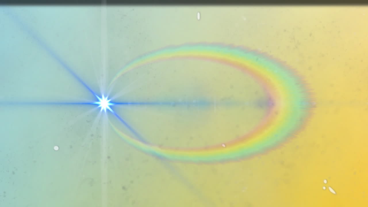 Bright blue-white starburst lens flare emitting wide light beam showing rainbow halo and speckles