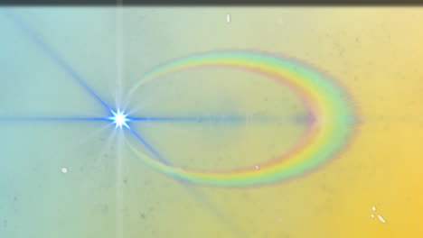 Bright blue-white starburst lens flare emitting wide light beam showing rainbow halo and speckles