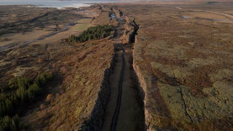 Aerial-forward-over-fault-or-crack-of-Thingvellir-National-Park-with-Oxararfoss-waterfall,-Iceland