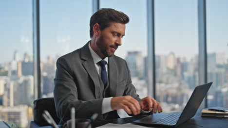 focused businessman looking papers at desk. smiling inspired man typing laptop