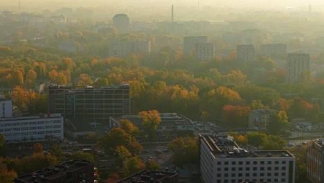 autumn sunrise above warsaw poland. drone shot of morning mist above apartment buildings, colorful trees and street traffic