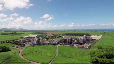una fábrica de azúcar en mauricio en medio de campos verdes bajo cielos azules, la industria se encuentra con la agricultura, vista aérea
