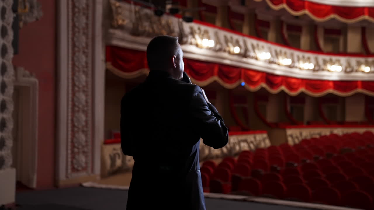 Young actor practicing speech in empty auditorium. He is standing on stage.