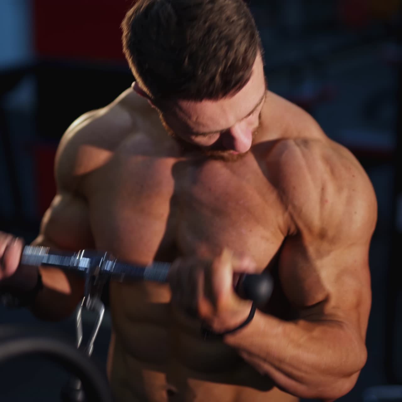 Training muscles. Sportsman pumping his trained body on a simulator. Strong trainer doing workout. Exercise to improve strength at fitness club. Close-up