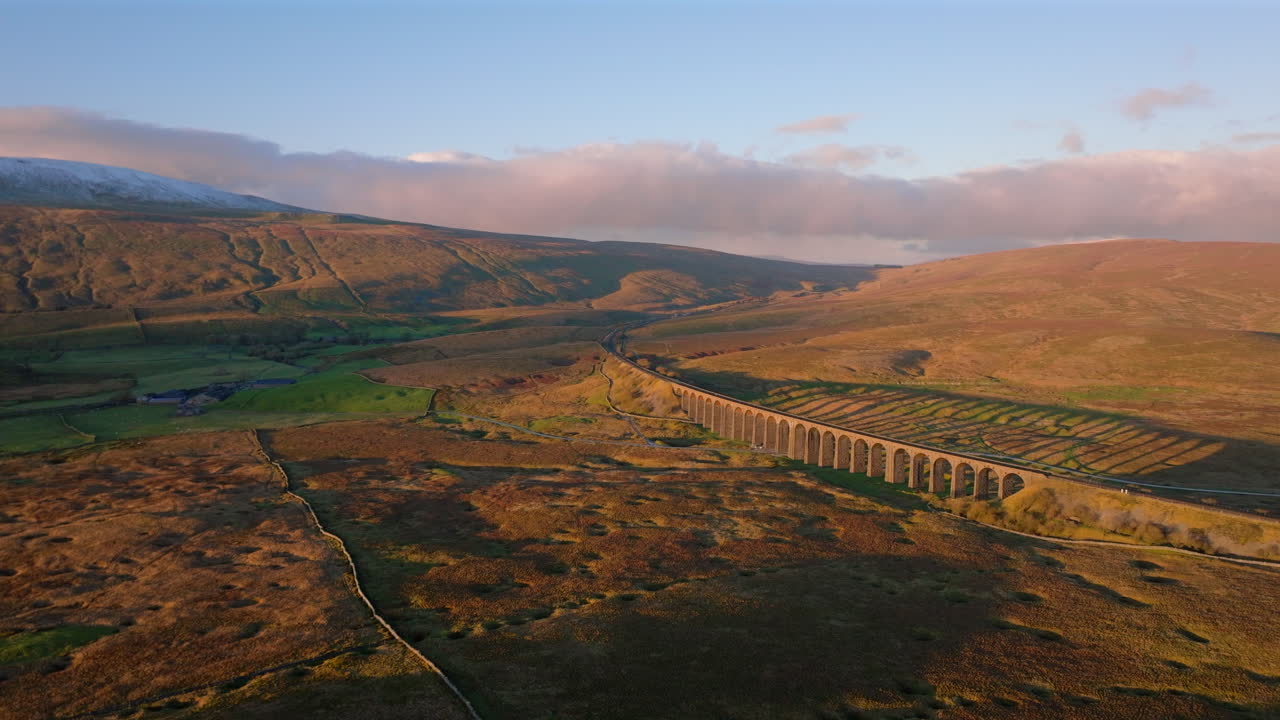 요크셔 즈 (yorkshire dales) 에서 해가 지는 황금시 (golden hour) 에 눈이 쌓인 뒤에 있는 리블헤드 다이아트 (ribblehead viaduct) 의 공중 드론 촬영