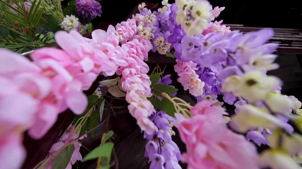 Vibrant pink and purple floral garlands cascade over a wooden beam in a traditional Chinese setting. Ideal for use in cultural documentaries or garden-themed projects.