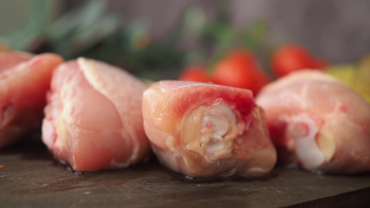 Primo piano di fusi di pollo crudi freschi su un tagliere di legno