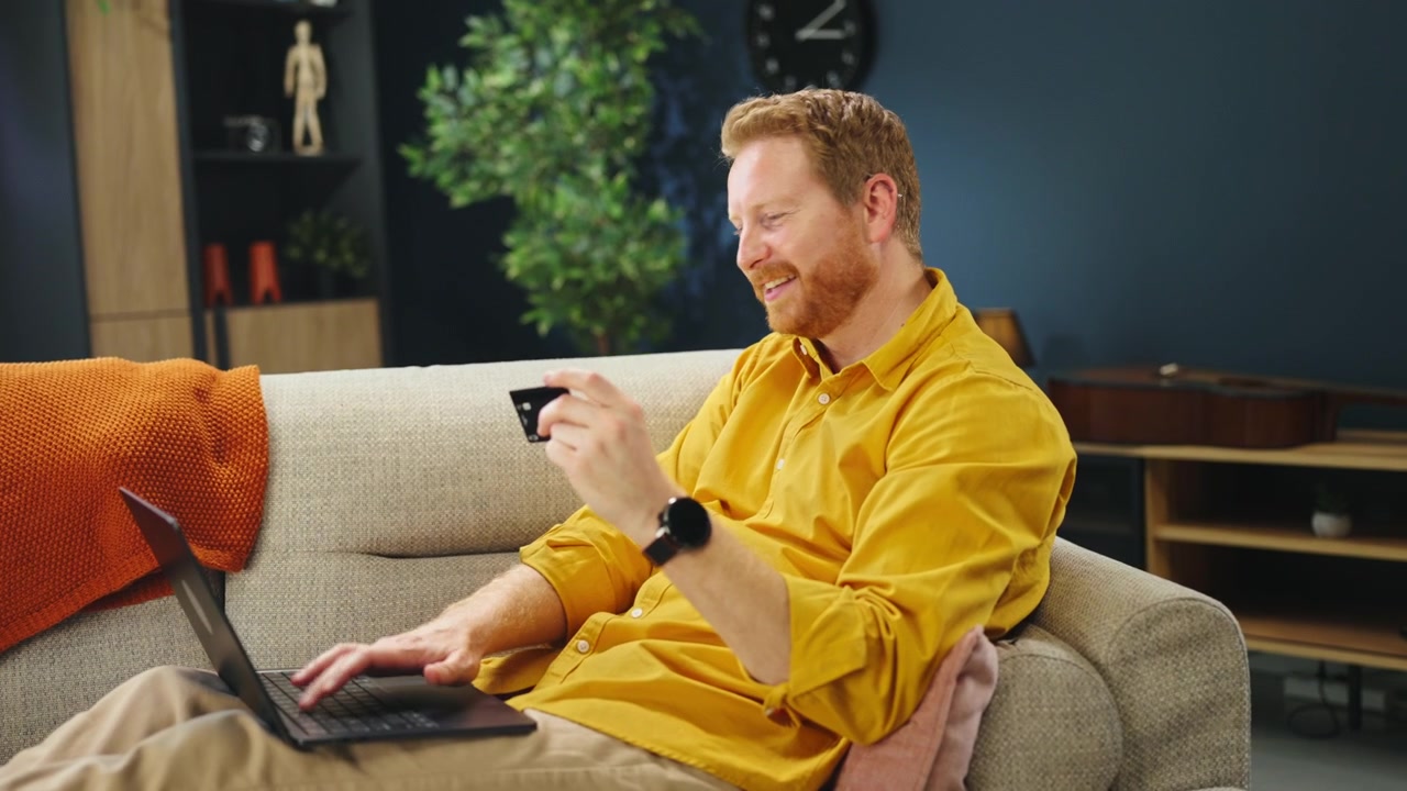Man Shopping Online with Credit Card on Laptop at Home