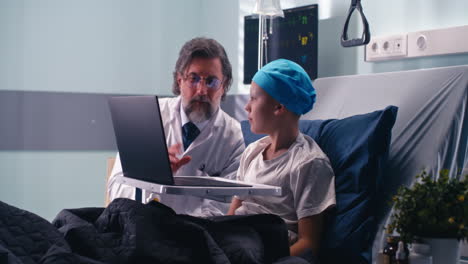 doctor consults with a child patient using a laptop in a hospital room