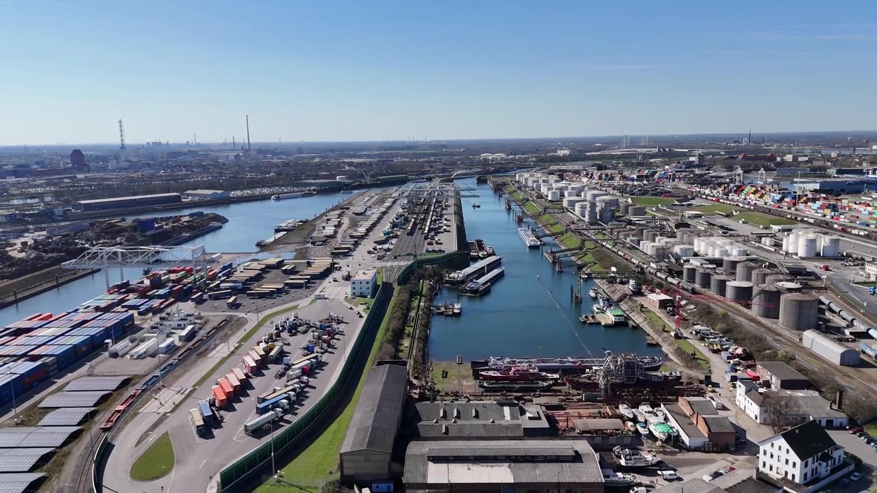 Wide backward drone flight revealing tank unloading berths container terminals silos and the large scale of Duisport.