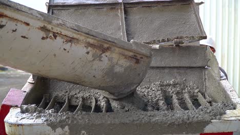 cement mix slowly falling from a conveyor into a container at a construction site