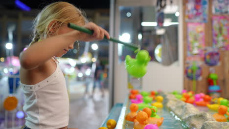 young girl playing a fishing game at an amusement park at night