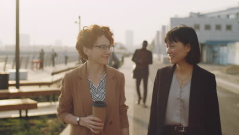 multiethnic female colleagues walking in city and talking
