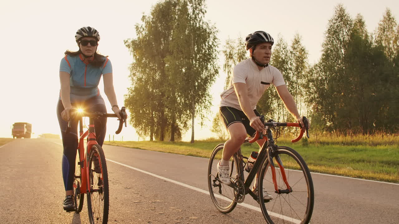 Steadicam shot of mountain biking couple riding on bike trail at sunset doing high.