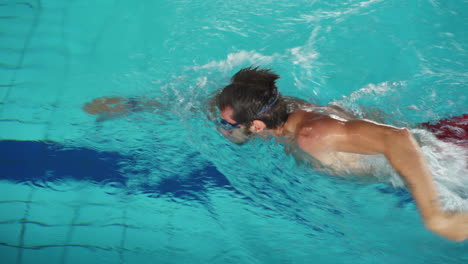 hombre caucásico nadando en la piscina usando la técnica de estilo libre