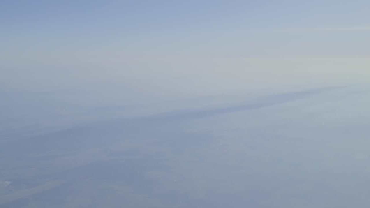Clouds with soft gradients and distant landscape below, calm atmosphere, aerial view