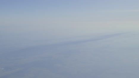 clouds with soft gradients and distant landscape below, calm atmosphere, aerial view
