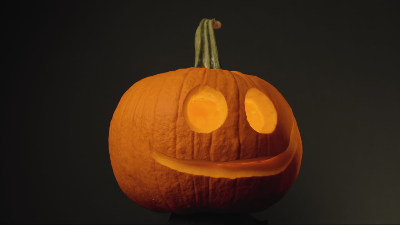 cabeza de calabaza - calabaza con ojos redondos tallados y boca en fondo negro