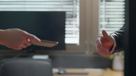hands exchanging smartphone in office and shake hands. business deal or digital transaction of confidential agreements. digital footprint evidence, phone is handed to detective or spy for forensics