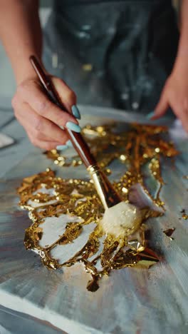 applying gold leaf to an abstract painting