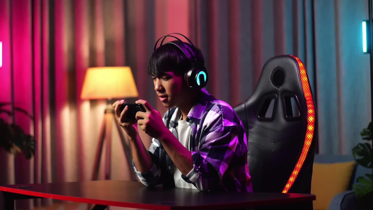 Excited Asian Teen Boy Gamer Playing Video Game On Smartphone