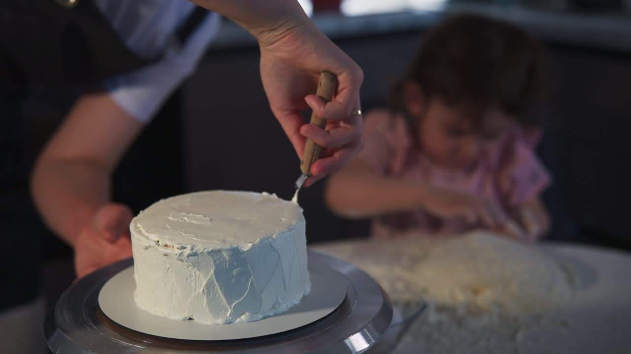 Genitore che decora una torta mentre il bambino gioca con la farina in cucina