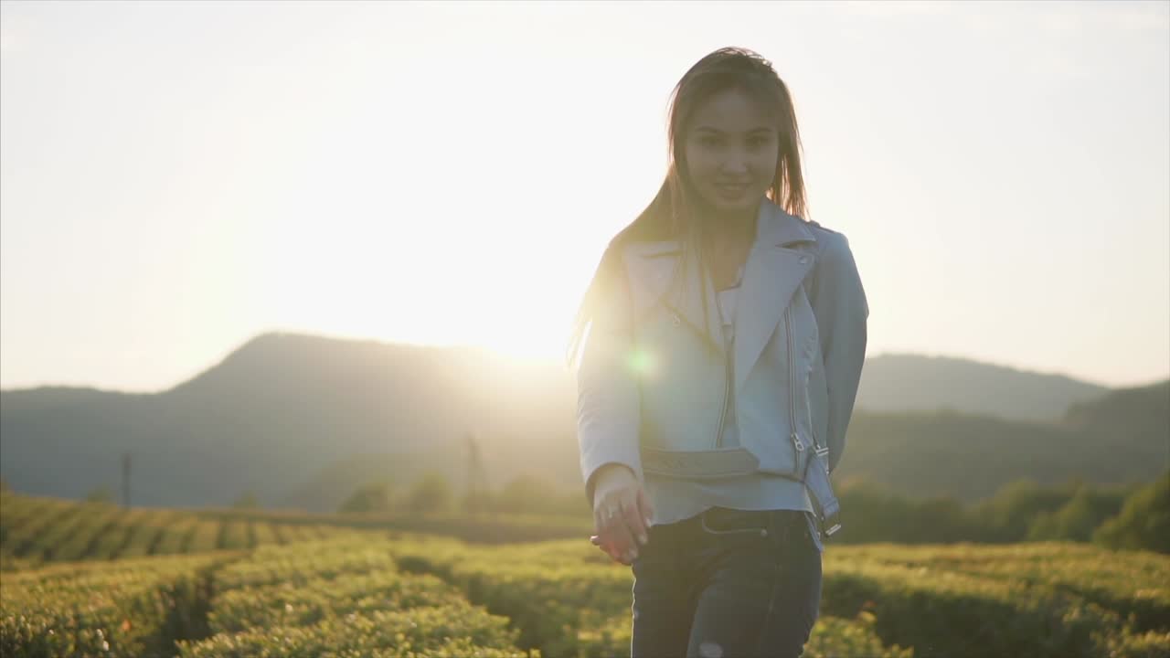 夕暮れの茶畑にいる若い女性