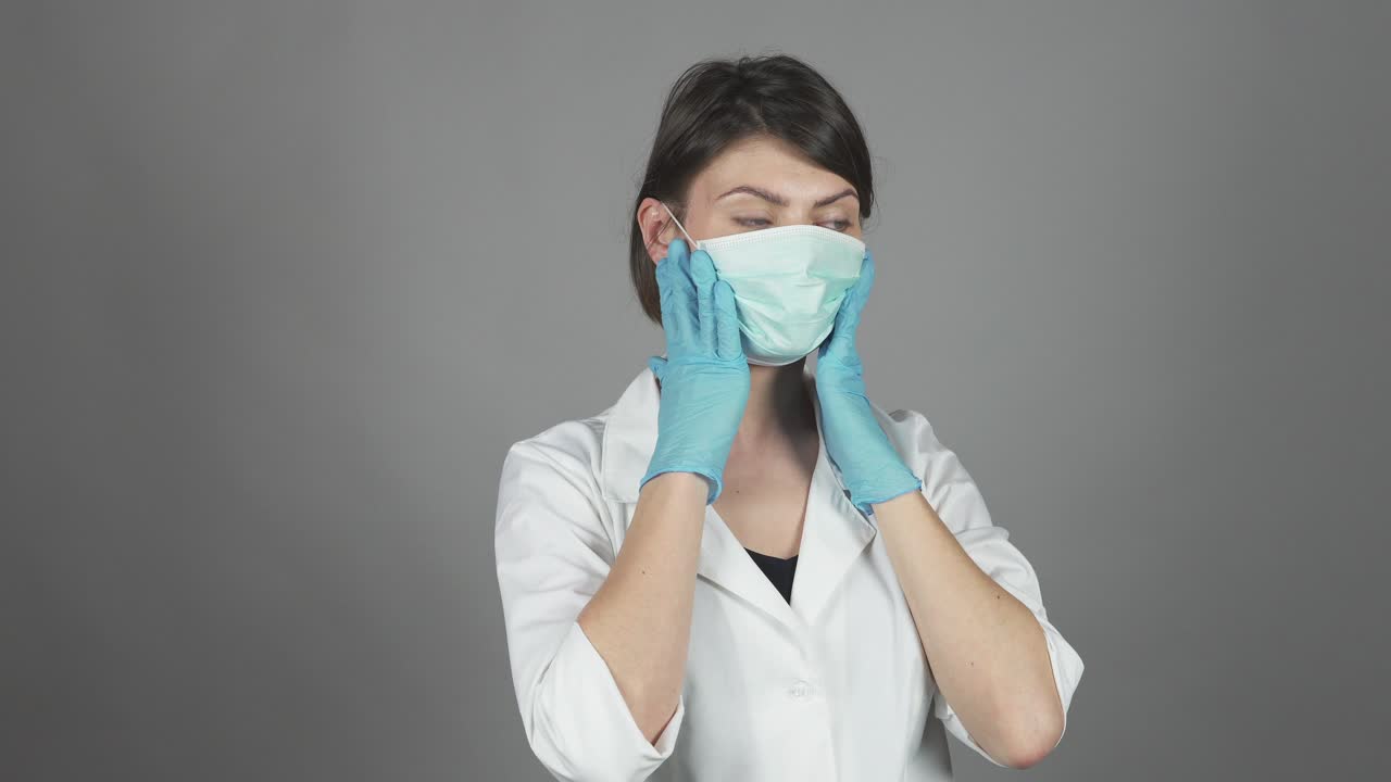 cirujana con guantes verdes preparándose para la operación, poniéndose la máscara. concepto de atención médica. filmado en 4k.