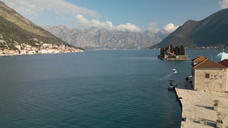 el vuelo del avión no tripulado hacia atrás revela nuestra dama de las rocas con hermosas montañas montenegrinas en el fondo