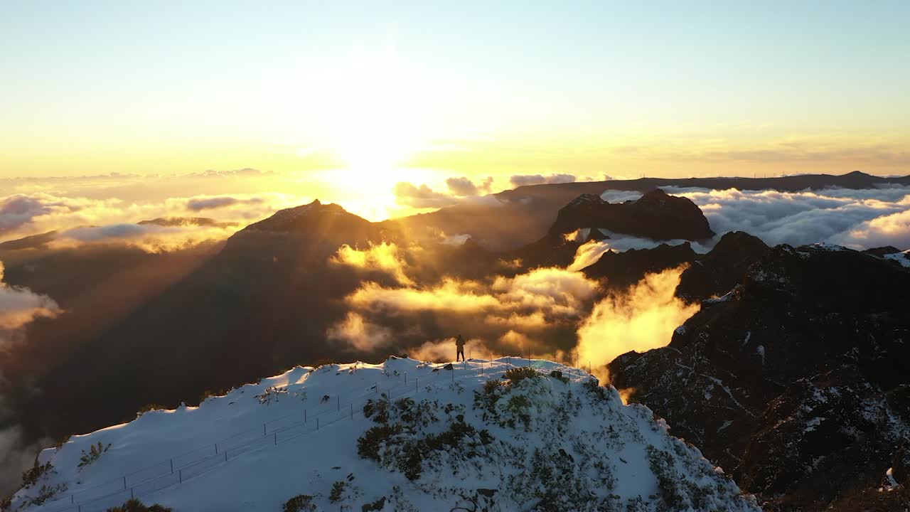 toma de drones de un hombre parado solo mirando la vista desde la cima de la montaña en madeira