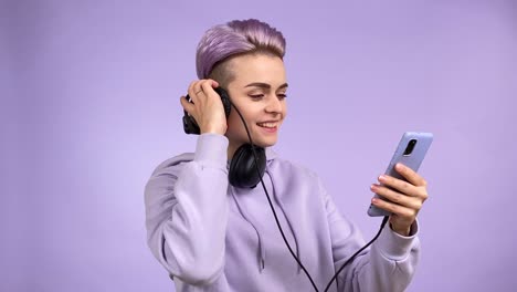 young woman in all purple listening music via smartphone headphones