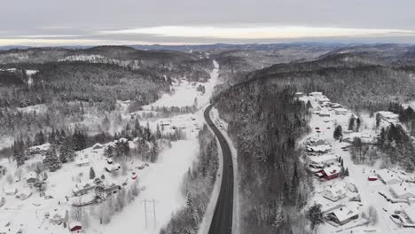 cars driving on long and winding highway through wintry landscape in norway