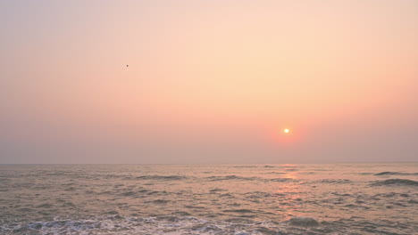 Sunset-over-the-sea,-slow-motion-of-foamy-sea-waves-slowly-rolling-towards-the-beach-in-Miami-Florida