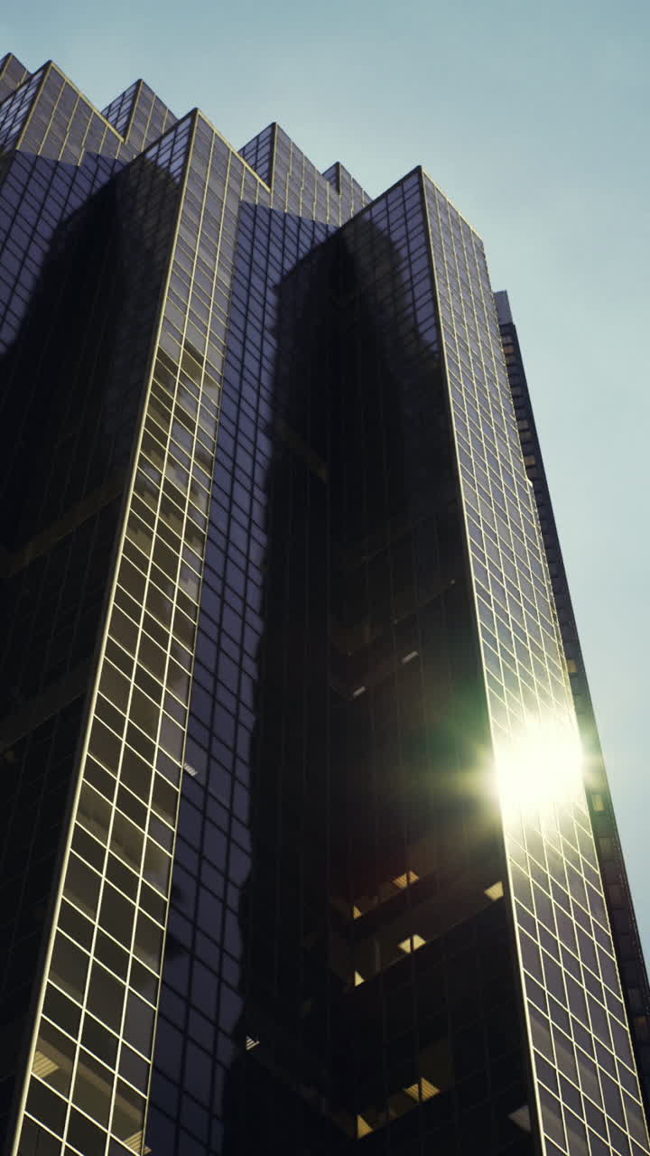 Arranha-céus se elevam contra um céu azul com a luz do sol refletindo no vidro