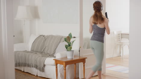 mujer joven feliz bailando firmando karaoke en casa usando auriculares celebrando con movimientos de baile divertidos divirtiéndose el fin de semana 4k