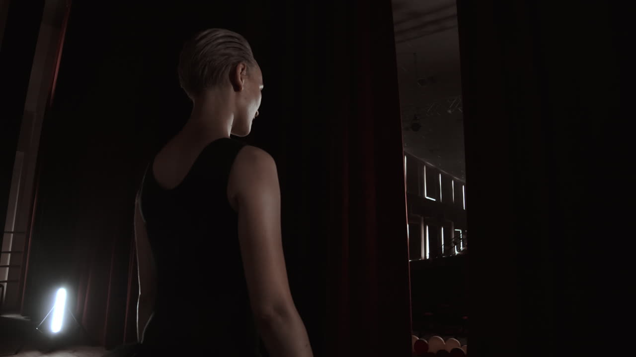 무대가 열리자 발레리나가 공연을 위해 무대에 들어갑니다. 여성의 힘, 부서지기, 연기, 실루, 느린 동작.