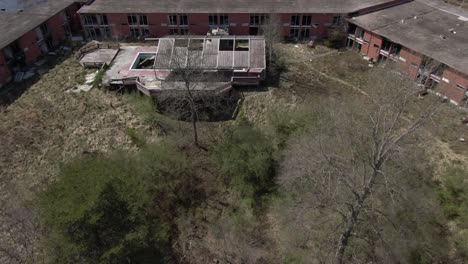 aerial drone footage dollying forward and panning down towards an abandoned hotel during late winter