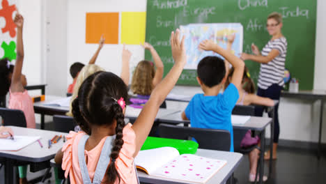 school kids raising hand in classroom