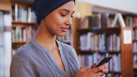 asian female student wearing a blue hijab and using a smartphone