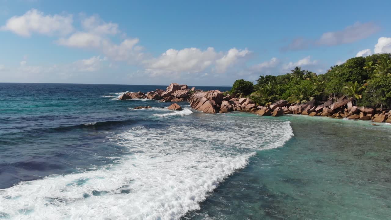 vista aérea siguiendo las olas rodando hacia las playas blancas y despobladas de anse coco, petit anse y grand anse en la digue, una isla de las seychelles