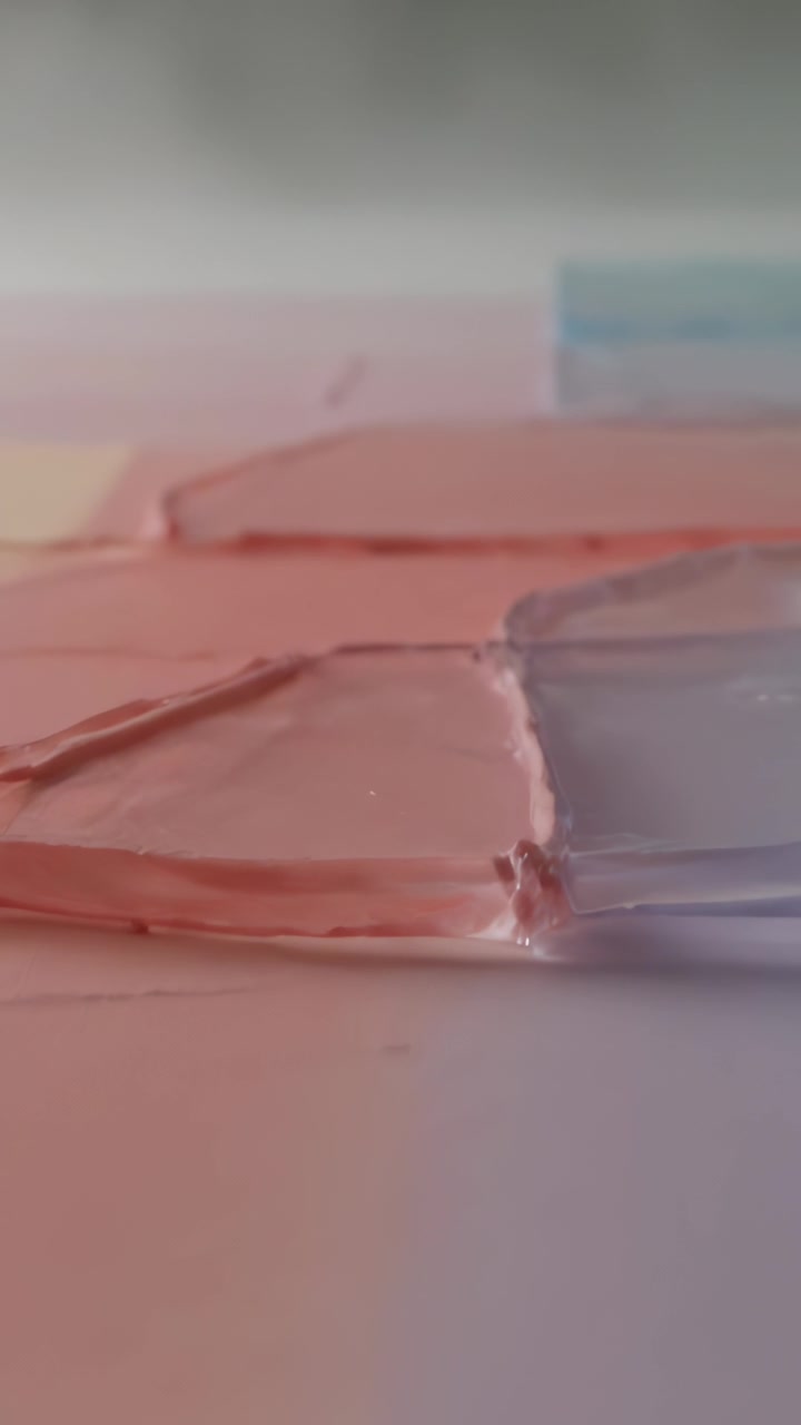 Video verticale: Telecamera in movimento che rivela campioni di gel rosa e lavanda su un foglio bianco, mostrando lucentezza.