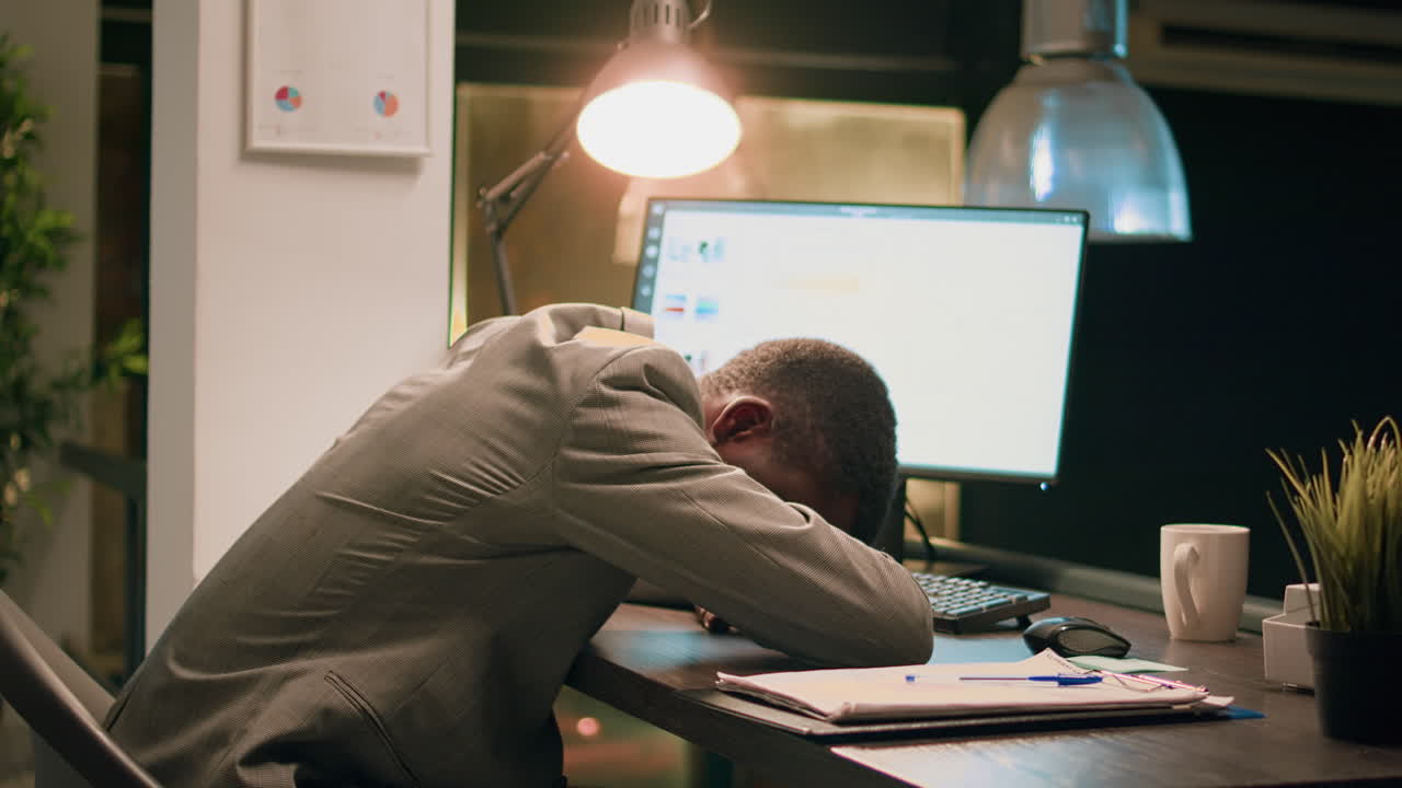 Exhausted Businessman Asleep at Desk in Office