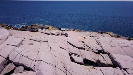 Aerial-flyover-of-a-rocky-shoreline-along-the-Atlantic-Ocean-on-a-bright,-sunny-day