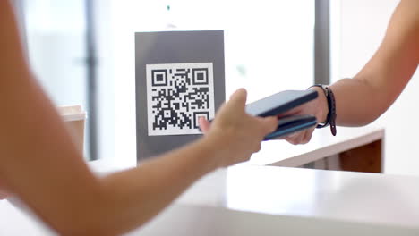 una joven biracial con un teléfono inteligente, escaneando un código qr