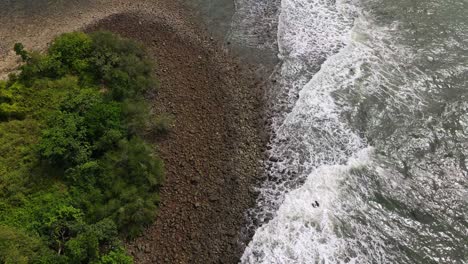 top view aerial above island pebble shoreline tide current surging along the coastline