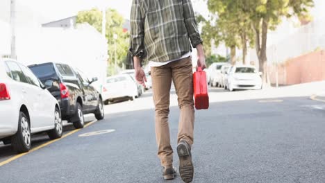 rear view of caucasian man walking in road carrying fuel jerrycan