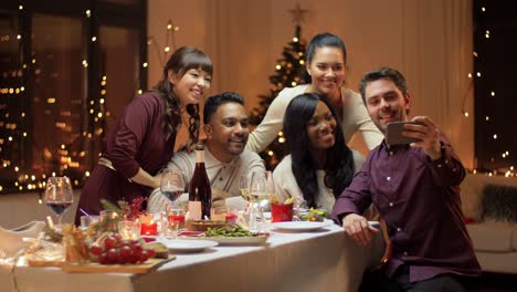 Winterferien,-Feiern-Und-Menschen-Konzept-Glückliche-Freunde-Mit-Weihnachtsessen-Zu-Hause-Und-Selfie-Mit-Sparphone