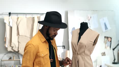 man tailor taking measurements from a garment to a mannequin in the sewing workshop