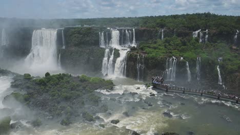 high above view of amazing tourism destination of tall rough waterfalls in rough rocky jungle landscape, tourist platform viewing close up huge splash zone hidden in iguazu falls