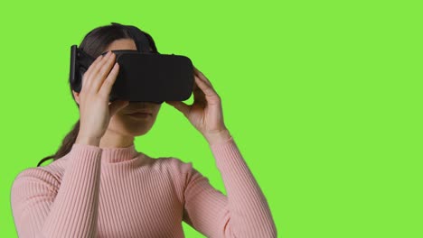 Mujer-Poniéndose-Un-Casco-De-Realidad-Virtual-E-Interactuando-Con-El-Fondo-Del-Estudio-De-Pantalla-Verde-1